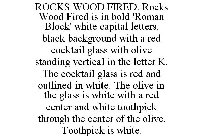 ROCKS WOOD FIRED. ROCKS WOOD FIRED IS IN BOLD 'ROMAN BLOCK' WHITE CAPITAL LETTERS, BLACK BACKGROUND WITH A RED COCKTAIL GLASS WITH OLIVE STANDING VERTICAL IN THE LETTER K. THE COCKTAIL GLASS IS RED AN