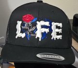 THE NAME IS LIFE THE I IS REPLACED WITH A ROSE THERE IS S&B AND BETWEEN THE ROSE IN THE F, THERE IS A GLOBE IN THE BACKGROUND